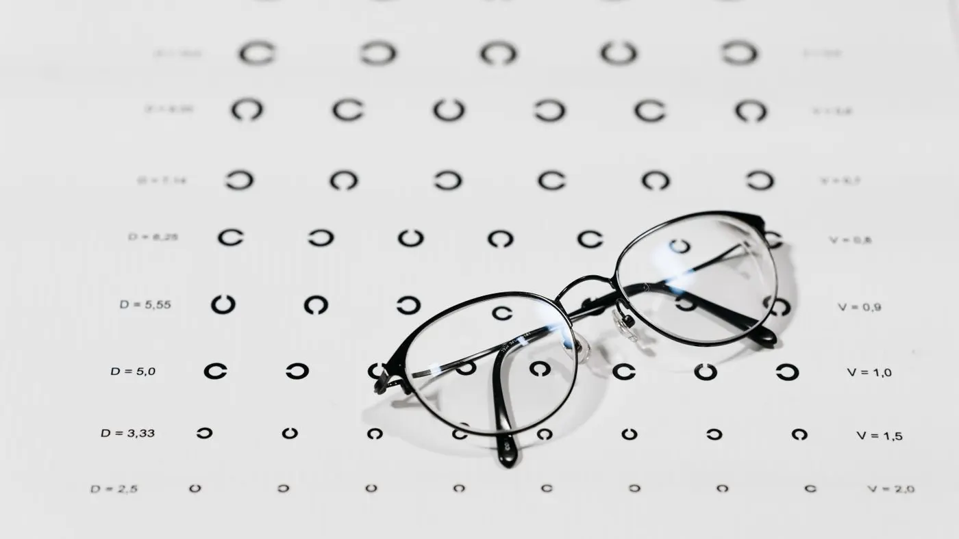 Gafas de montura fina apoyadas sobre una tabla optométrica de anillos abiertos, para la guía sobre agudeza visual